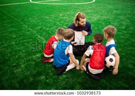 Young trainer showing his football team sketch of moving scheme while preparing for competition