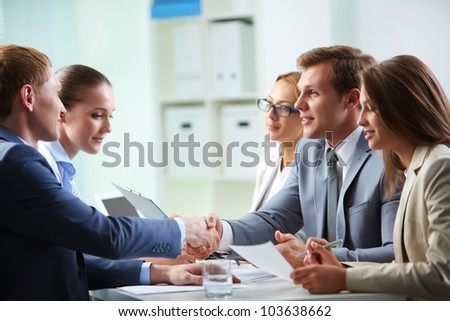Image of confident businessmen handshaking at meeting