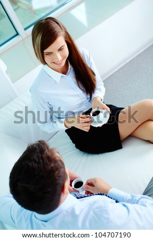 Photo of friendly business partners talking while drinking coffee in office