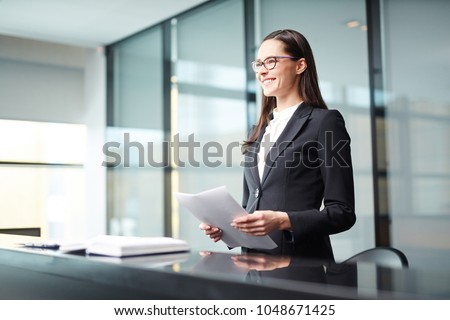 Young businesswoman or delegate with papers making report at conference or political summit