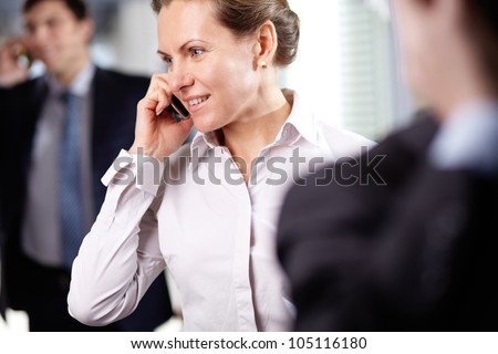 Image of modern businesswoman with cellular phone in working environment