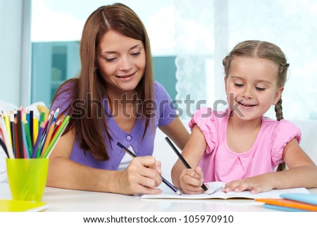 Mother and daughter spending time together at home drawing