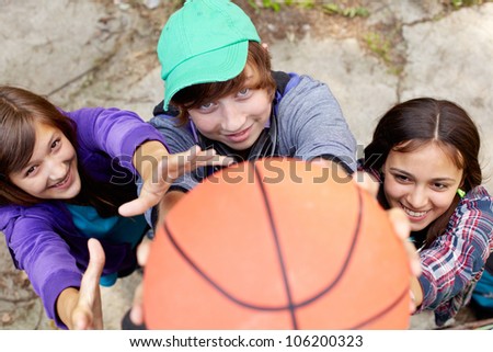 Cheerful teens playing basketball in the street holding the ball close to the camera