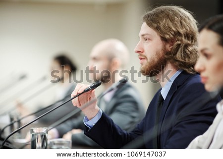 Young serious speaker making report for audience at political conference or forum