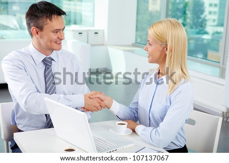 Portrait of successful associates handshaking after striking deal