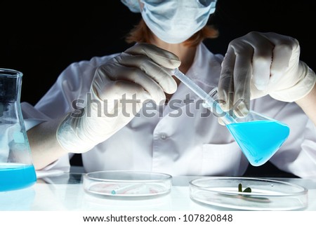 Lab worker withdrawing substance from beaker into pipette Lab worker withdrawing substance from beaker into pipette