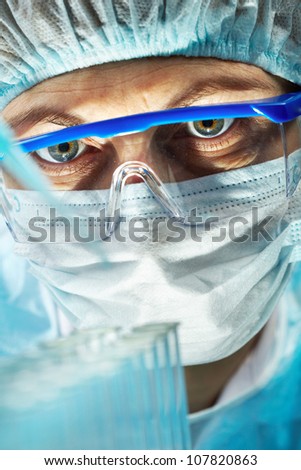Close-up of a woman wearing protective mask and eyeglasses working with bio samples
