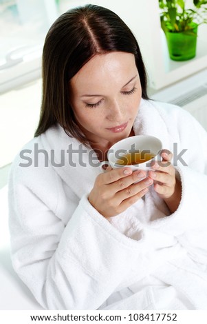 Vertical shot of an adorable young lady enjoying tea in spa salon