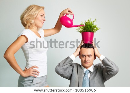 Young woman giving water to the plant on the head of the entrepreneur