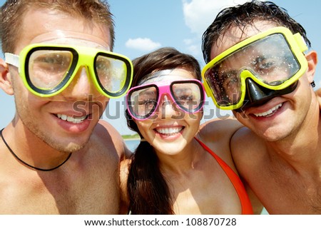 Portrait of three cheerful friends wearing scuba masks and smiling at camera
