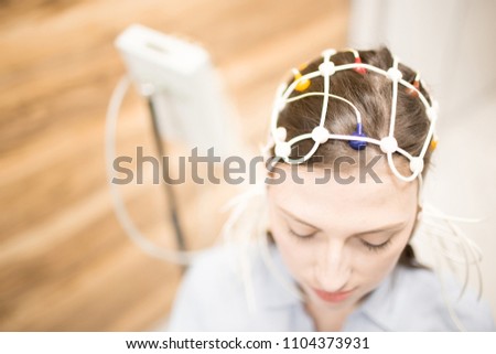 Young female with electrode equipment on her head having clinical test in hospital