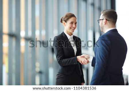 Young smiling businesswoman giving handshake to foreign business partner at meeting