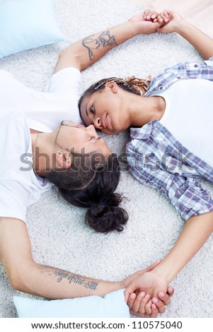 Image of young guy and his girlfriend lying on the floor and holding by hands