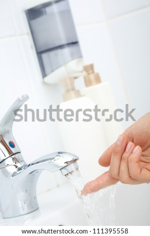 Close-up of human finger trying how hot the water is