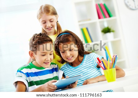 Portrait of happy classmates at workplace using digital tablet