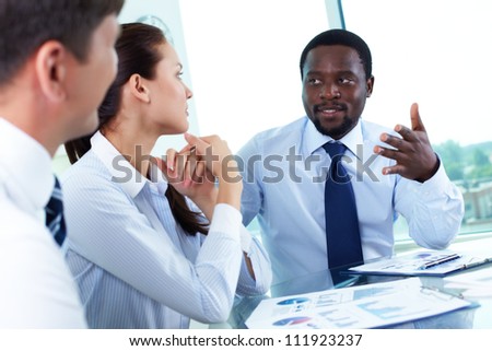 Portrait of serious boss talking to his employees at meeting