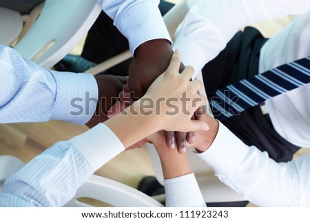 Above view of business partners hands on top of each other symbolizing companionship and unity