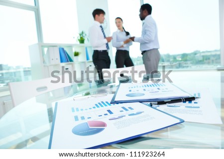 Image of business documents with working team communicating at background Image of business documents with working team communicating at background