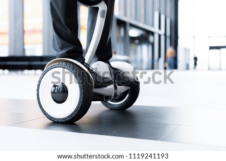 Human legs and feet on hoverboard over floor of large contemporary lounge