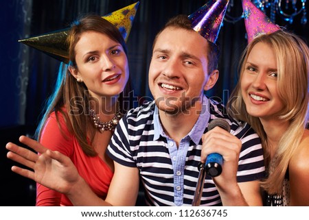 Portrait of happy people singing in microphone in the karaoke bar
