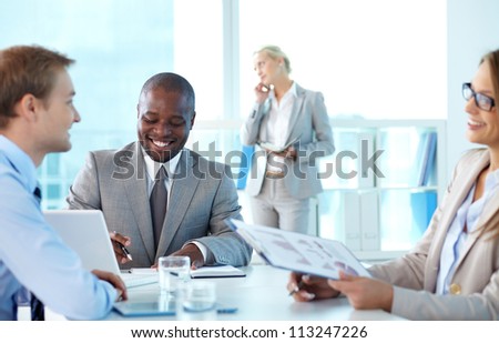 Portrait of confident boss smiling while his partners interacting at meeting