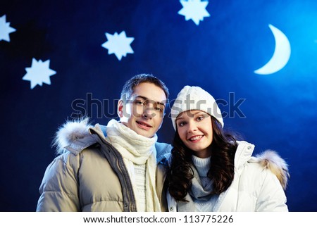 Portrait of happy couple looking at camera with moon and stars above their heads