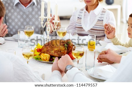 Family members giving thanks to God at festive table with roasted turkey on it