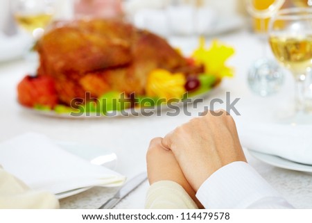 Family members giving thanks to God at festive table while holding each other by hands