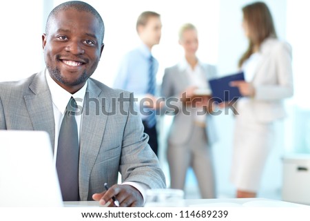 Portrait of happy boss looking at camera in working environment