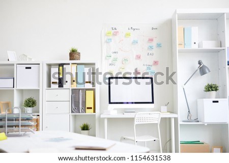 Contemporary office with shelves, desks, computer monitor, chair, lamp and other supplies