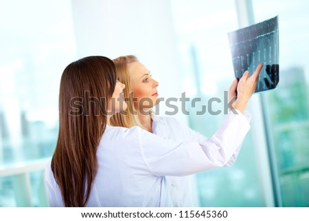 Portrait of young doctor commenting x-ray exam results to her colleague