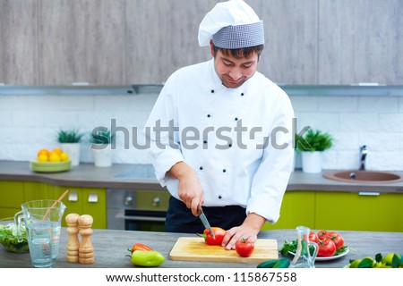 Image of male chef with knife cutting vegs on wooden board