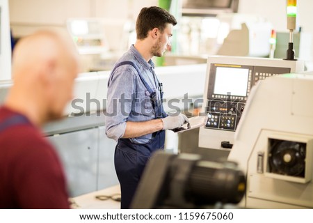 Young engineer with tablet pc manufacturing industry with big modern computer machine