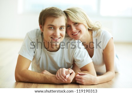 Image of young guy and his girlfriend lying on the floor and looking at camera