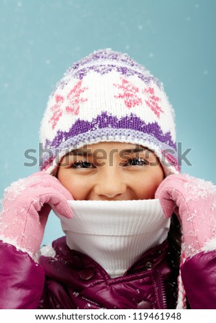 Face of pretty woman in knitted winter cap and gloves looking at camera