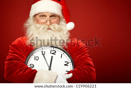 Photo of happy Santa holding clock showing five minutes to midnight