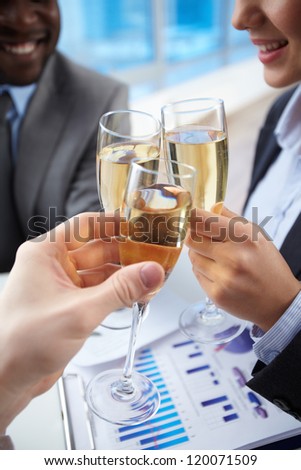 Close-up of business partners hands cheering up with flutes of golden champagne