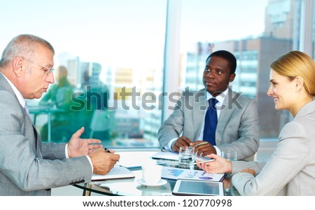 Portrait of serious boss looking into his notepad during explanation with pretty secretary looking at him