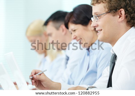 Business people sitting in a row and working, focus on successful young man