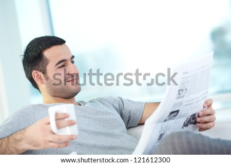 A young guy with newspaper reading it