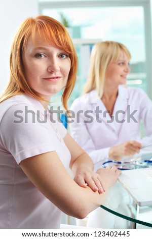 Portrait of female patient looking at camera with doctor on background