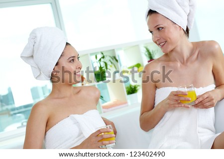Girls in bath towels drinking juice in spa salon