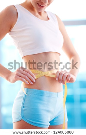 Image of slender woman measuring her waist