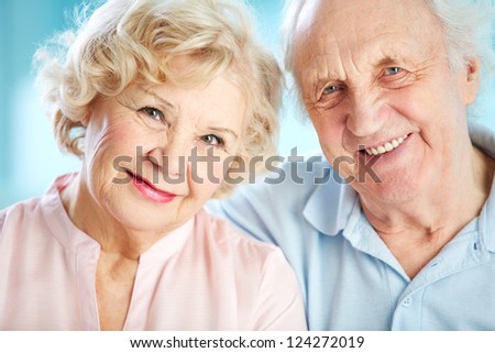 Close-up portrait of a charming elder couple looking at the viewer with a smile