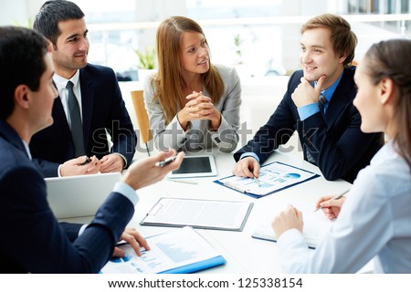 Image Of Business Partners Discussing Documents And Ideas At Meeting