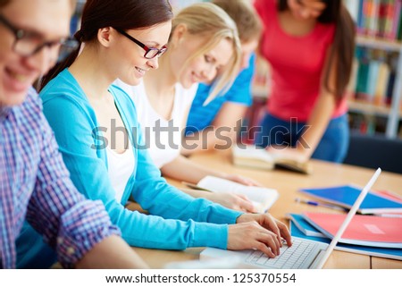 Portrait of pretty girl typing on laptop among her group mates at lesson