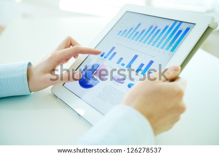 Business Person Analyzing Financial Statistics Displayed On The Tablet Screen