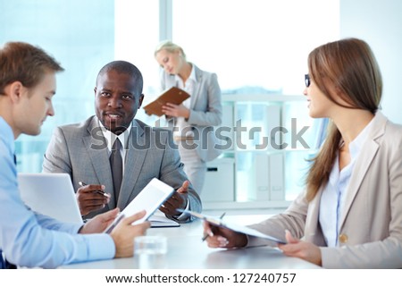Portrait of confident boss looking at employee during interaction at meeting Portrait of confident boss looking at employee during interaction at meeting
