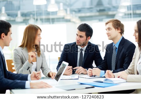 Image of business partners listening to female employee at meeting