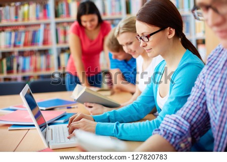 Portrait of pretty girl typing on laptop among her group mates at lesson